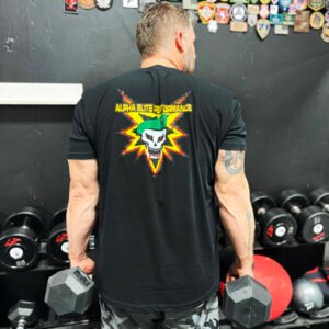 A person wearing an Alpha Elite Performance shirt lifts a dumbbell in a gym, with various fitness equipment visible in the background, demonstrating strength and focus.